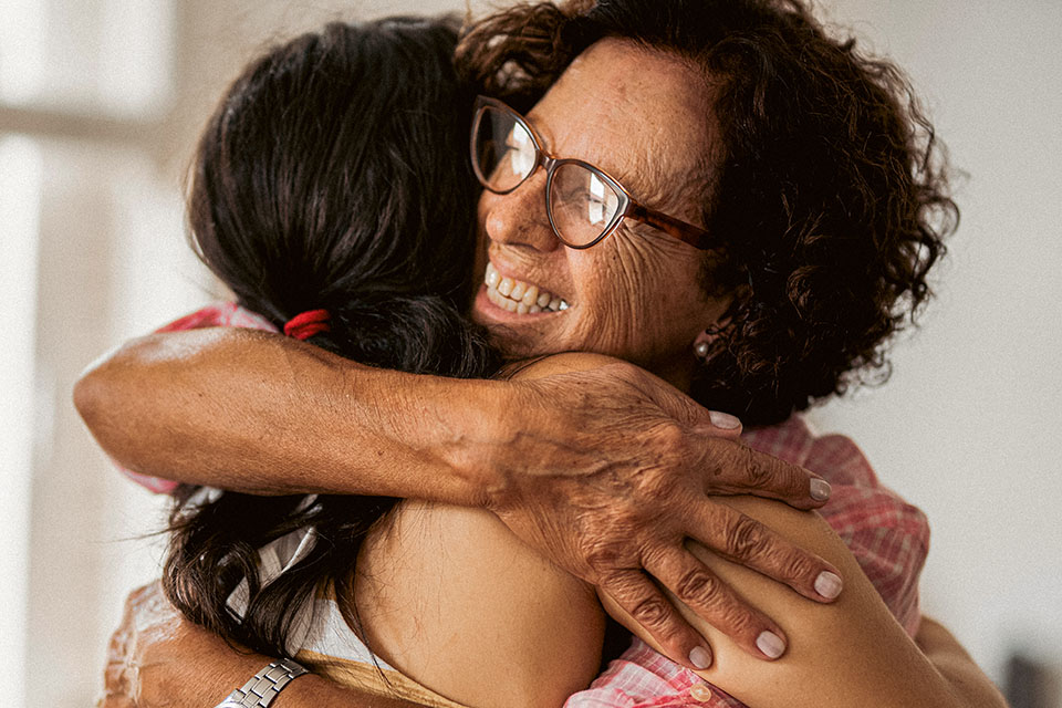 Mature woman hugging her adult daughter and smiling during a visit together